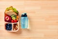 Kids school lunch box with sandwich, fruits, vegetables, blueberries, nuts and bottle of water on wooden table Royalty Free Stock Photo