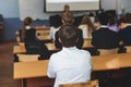 Kids in school writing and taking notes, teens pupils behind desks during the lesson listen to teacher lecture, classroom with Royalty Free Stock Photo