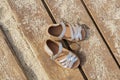 Kids silver leather sandals on wooden board with sand in sunny day Royalty Free Stock Photo