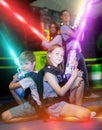 Kids sitting back to back on beams with laser pistols Royalty Free Stock Photo