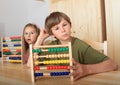 Kids sitting behind wooden table with abacuses Royalty Free Stock Photo