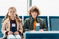 Kids sitting on blue chairs, holding passports and tickets in waiting hall Royalty Free Stock Photo