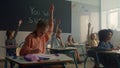 Kids sitting at desks in classroom. Clever pupils raising hands at lesson Royalty Free Stock Photo