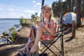 Kids sitting on touristic armchair, eating croissants and looking at sea during vacation at campsite