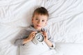 Kids sleeping concept with asleep little boy in bed with alarm clock