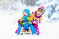 Kids on sleigh ride. Children sledding. Winter snow fun. Royalty Free Stock Photo