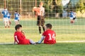Kids soccer players sitting behind goal watching football match Royalty Free Stock Photo