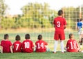 Kids soccer players sitting behind goal watching football match Royalty Free Stock Photo