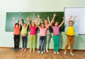 Kids stand with arms up in line near blackboard Royalty Free Stock Photo