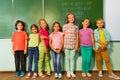 Kids stand in line near the blackboard and smile Royalty Free Stock Photo