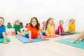 Kids stretching backs on yoga mats in sports club