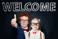 Kids student little boy and girl on blackboard background with welcome inscription
