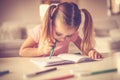 Kids stuff. Little girl trying draw with pencil in her mouth. Royalty Free Stock Photo