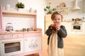 Kids and sweets concept. Adorable toddler girl eating easter cake near toy kitchen in light room Royalty Free Stock Photo