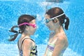 Kids swim in swimming pool underwater, little active girls have fun under water, children fitness and sport Royalty Free Stock Photo