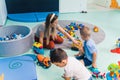 kids and a teacher having fun in kindergarten, the floor is full of balls, building blocks, cars and other toys Royalty Free Stock Photo