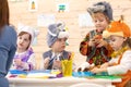 Kids with teacher make hands crafts in kindergarten. Children prepare to christmas. Group of preschoolers on lesson in Royalty Free Stock Photo