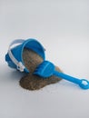 Kids toy bucket spilling beach sand and a rake on a white background Royalty Free Stock Photo