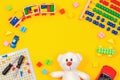 Kids toys background. Teddy bear, wooden train, colorful blocks, toy tools kit, cars, abacus on yellow background