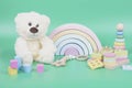 Kids toys collection. Teddy bear, wooden rainbow and baby educational toys on light green background