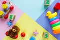 Kids toys: pyramid, wooden blocks, bear, train frame on colored background. Top view. Flat lay.