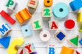 Kids toys: pyramid, wooden blocks, train frame on white wooden background. Education, games for preschool. Top view.