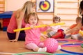 Kids and trainer playing with sport equipment in kindergarten gym