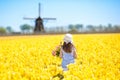Kids in tulip flower field. Windmill in Holland