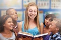 Kids, tutor and reading a book in classroom for knowledge, learning or education with happiness. Group, students or Royalty Free Stock Photo