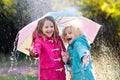 Kids with umbrella playing in autumn shower rain