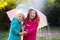 Kids with umbrella playing in autumn shower rain