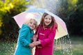 Kids with umbrella playing in autumn shower rain.