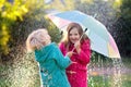 Kids with umbrella playing in autumn shower rain