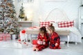 Kids unwrap gifts from Santa sitting by the bed on Christmas morning