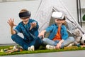 kids using virtual reality headsets and gesturing by hands near wigwam
