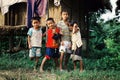 kids waiting outside of their bamboo hut style home