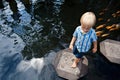 Kids walk by stepping stones, feeding koi fishes in pond