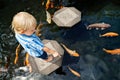 Kids walk by stepping stones, feeding koi fishes in pond