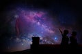 Kids watching the stars on the roof of their house at night.