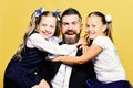 Kids wearing school clothes and bows sitting near bearded teacher