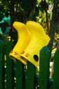 Kids yellow rubber rain boots on green fence. Games and playing having fun, jumping in puddles in rainy weather in