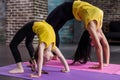 Kids yoga female teacher training a child girl standing in wheel pose working out in stylish sports studio