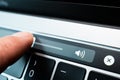 Kiev, Ukraine - August 9, 2022: Finger adjust volume slider on touch bar apple macbook pro closeup