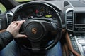 Kiev, Ukraine; July 4, 2013; A man holds the steering wheel of a luxury car. Gold ring on his hand. Porsche Cayenne