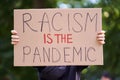 Kiev, Ukraine - July 31 2020: Racism is the pandemic poster which person is holding. Stop racism concept. Black Lives Royalty Free Stock Photo