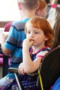 Kiev, Ukraine - March 3, 2018: A very beautiful little red-haired girl is sitting at a table and looking into the distance