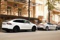 Kiev, Ukraine - May 22, 2021: White electric car Tesla Model X and Gray american muscle car Chevrolet Camaro parked in the city