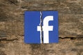 Facebook icon printed on paper, torn and put on old wooden backg