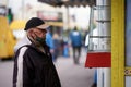 Kiev, Ukraine, 20.05.2020: Old grandfather, wearing a medical mask, wearing a cap, looks at an empty counter. Poor and homeless