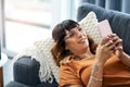 Kill time productively on your phone. a young woman using her cellphone while relaxing on the sofa at home.